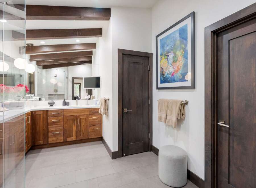 Experience luxury in this modern bathroom featuring a spacious double vanity with rich walnut cabinetry and a sleek white countertop.