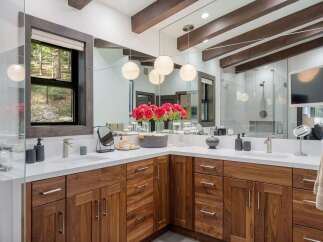 Experience luxury in this stunning bathroom featuring a spacious double vanity with rich walnut cabinetry and sleek quartz countertops.