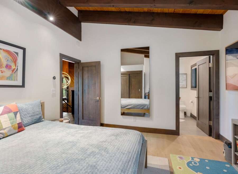 Experience modern comfort in this inviting bedroom, featuring a plush bed adorned with colorful pillows and a cozy quilted blanket.