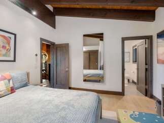 Experience modern comfort in this inviting bedroom, featuring a plush bed adorned with colorful pillows and a cozy quilted blanket.