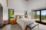 Experience serene mountain living in this beautifully appointed bedroom, featuring a spacious king-sized bed and large windows that frame breathtaking forest and lake views.
