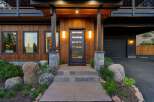 Experience modern mountain living in this stunning home, featuring a striking wood exterior and a sleek glass-paneled front door.