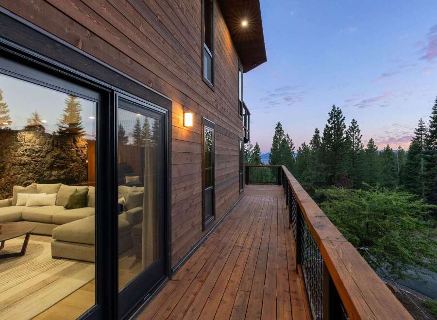 Experience seamless indoor-outdoor living with this stunning modern home featuring expansive sliding glass doors that open onto a spacious wooden deck.