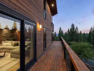 Experience seamless indoor-outdoor living with this stunning modern home featuring expansive sliding glass doors that open onto a spacious wooden deck.