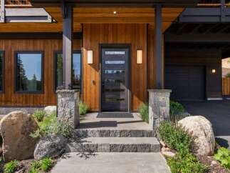 Experience modern mountain living with this stunning home featuring a striking wood exterior and a sleek, contemporary front door.