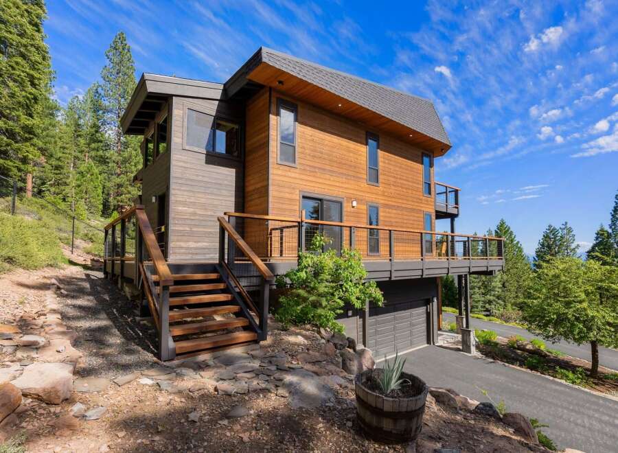 Experience modern mountain living in this stunning contemporary home, featuring warm wood siding and expansive decks perfect for enjoying the surrounding forest views.