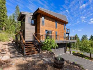 Experience modern mountain living in this stunning contemporary home, featuring warm wood siding and expansive decks perfect for enjoying the surrounding forest views.