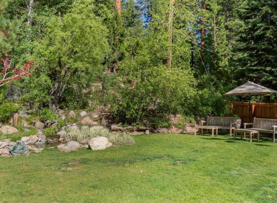 Enjoy the serene backyard oasis featuring a charming water feature and lush greenery, perfect for relaxation.