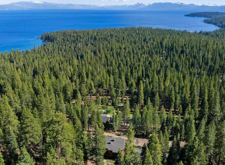 Nestled within a dense forest, this property offers a serene escape with stunning lake views in the distance.