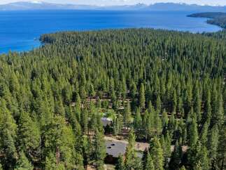 Nestled within a dense forest, this property offers a serene escape with stunning lake views in the distance.