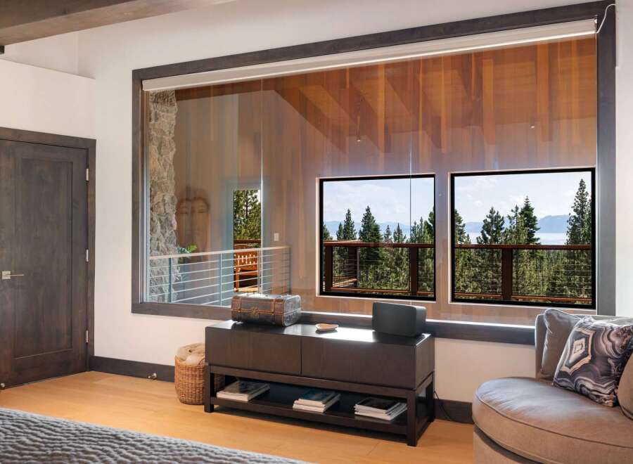 Experience breathtaking lake and mountain views from this stunning bedroom, featuring expansive windows that bring the outdoors in.