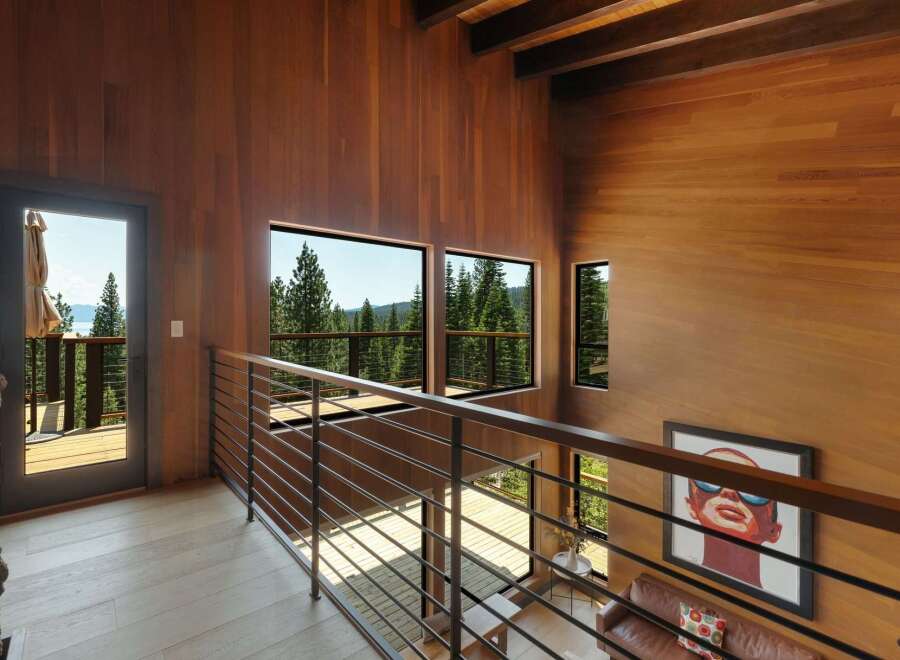 Experience breathtaking natural beauty from this stunning modern home, featuring expansive windows that frame panoramic views of lush forests and a serene lake.