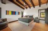 Experience modern mountain living in this stunning bedroom featuring a vaulted wood-beamed ceiling and a striking abstract art piece.