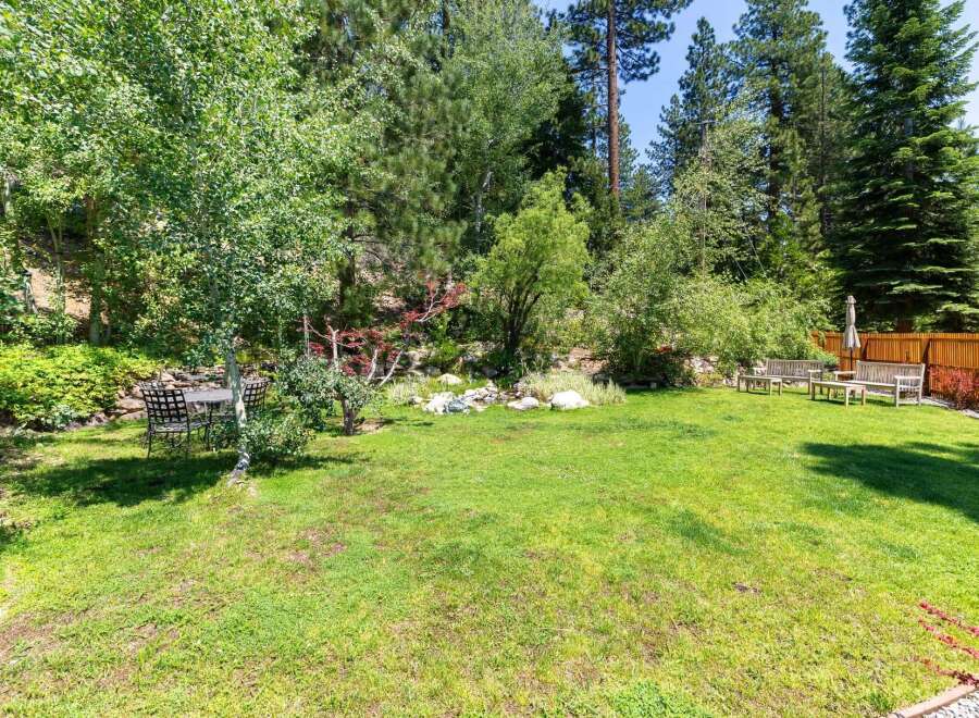 Enjoy the serene beauty of this backyard oasis, complete with lush green grass and mature trees providing ample shade.