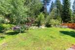 Enjoy the serene beauty of this backyard oasis, complete with lush green grass and mature trees providing ample shade.