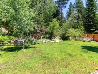 Enjoy the serene beauty of this backyard oasis, complete with lush green grass and mature trees providing ample shade.