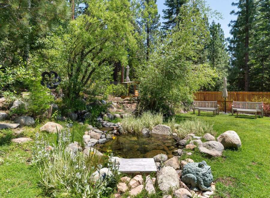 Escape to your private oasis with this stunning backyard featuring a tranquil water feature and lush greenery.