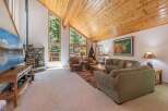 Experience rustic charm in this spacious living room, featuring a stunning stone fireplace and a soaring wood-paneled vaulted ceiling.
