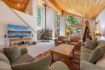 Experience rustic charm in this spacious living room, featuring a striking stone fireplace and a soaring wood-paneled ceiling.