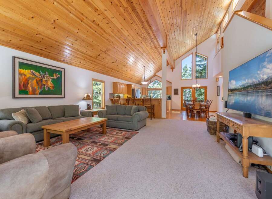 Experience rustic charm in this spacious living area, featuring a vaulted wood-paneled ceiling and a large stone fireplace.