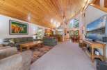 Experience rustic charm in this spacious living area, featuring a vaulted wood-paneled ceiling and a large stone fireplace.