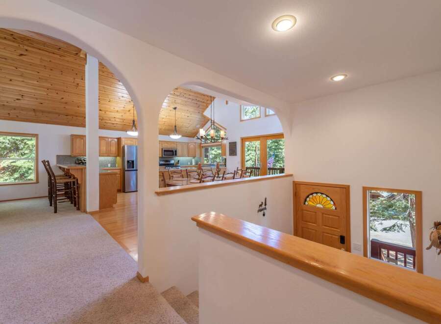 Step into this charming home featuring an open-concept living space with a vaulted, wood-paneled ceiling and a cozy kitchen area.
