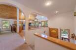 Step into this charming home featuring an open-concept living space with a vaulted, wood-paneled ceiling and a cozy kitchen area.