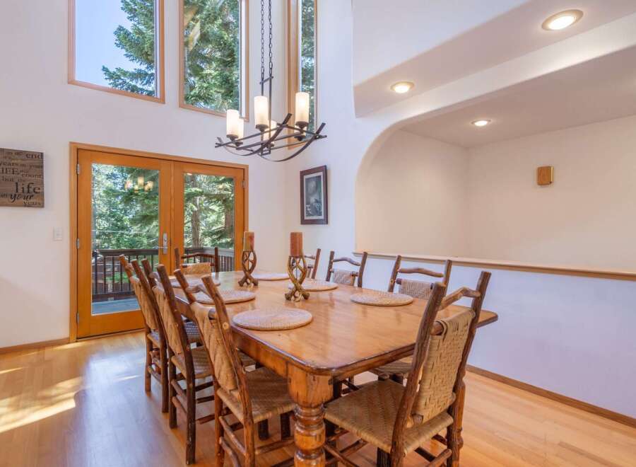 Experience elegant dining in this spacious room, featuring a large wooden table set for eight and a striking chandelier overhead.