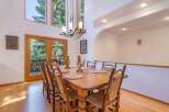 Experience elegant dining in this spacious room, featuring a large wooden table set for eight and a striking chandelier overhead.