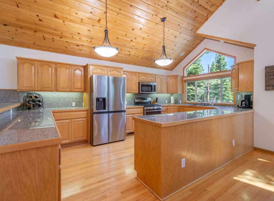 Experience the warmth of this inviting kitchen, featuring beautiful natural wood cabinetry and a stunning vaulted wood-paneled ceiling.