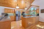 Experience the warmth of this inviting kitchen, featuring beautiful natural wood cabinetry and a stunning vaulted wood-paneled ceiling.