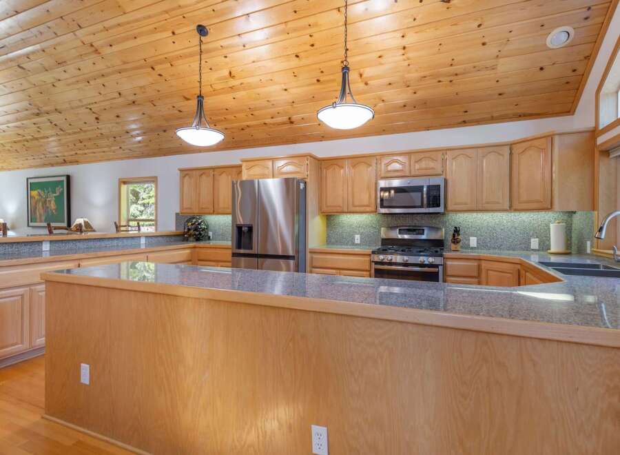 Experience the warmth of this inviting kitchen, featuring beautiful natural wood cabinetry and a spacious granite-topped island perfect for meal prep and casual dining.