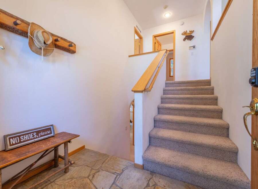 Welcome guests into this charming entryway featuring a rustic wooden bench and a 'No Shoes, Please' sign, setting a cozy tone.