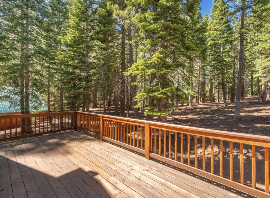Enjoy the serene mountain lifestyle from this spacious wooden deck, perfect for outdoor entertaining or simply relaxing amidst the towering pine trees.