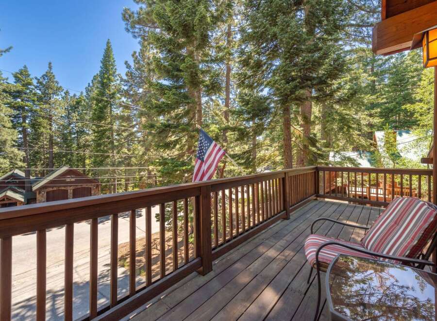 Enjoy the serene mountain views from this charming wooden deck, complete with comfortable seating and a glass-top table.
