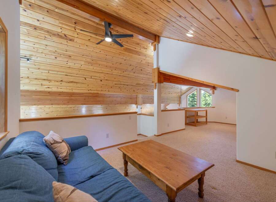 Experience rustic charm in this loft living area, featuring a vaulted wood-paneled ceiling and a cozy blue sofa.