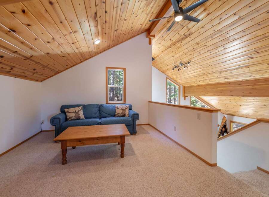 Experience rustic charm in this cozy living space featuring a comfortable blue sofa adorned with decorative pillows and a sturdy wooden coffee table.