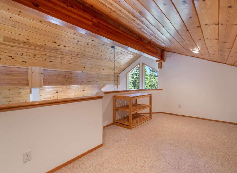 Ascend to this charming loft space, featuring a vaulted wood-paneled ceiling and a picturesque window offering serene forest views.