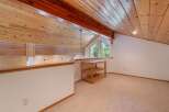 Ascend to this charming loft space, featuring a vaulted wood-paneled ceiling and a picturesque window offering serene forest views.