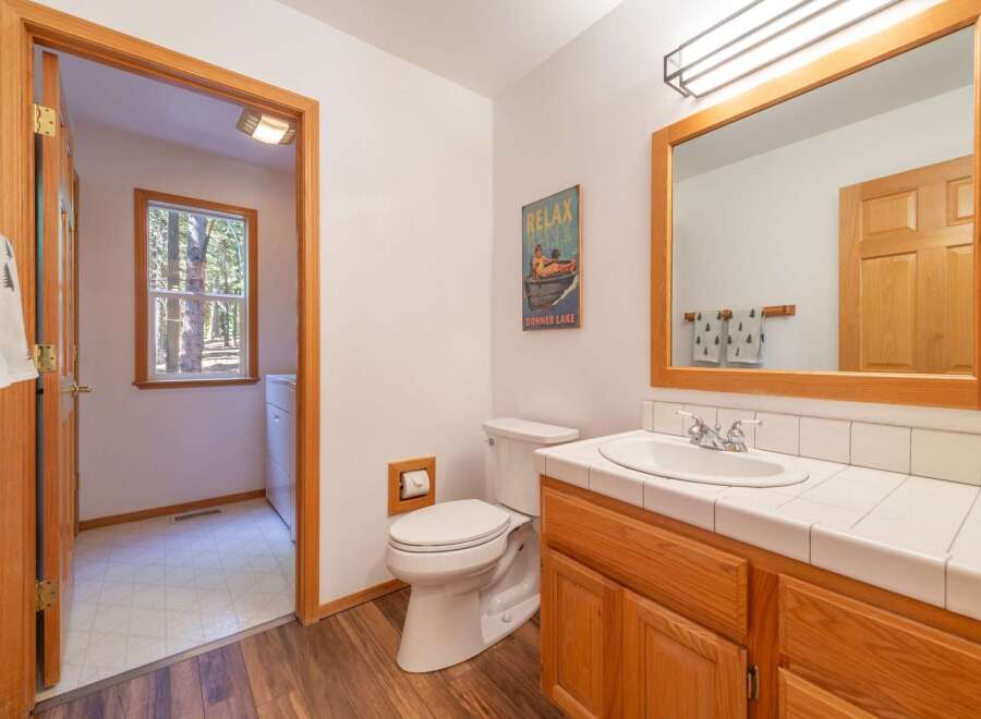 This charming bathroom features a classic wooden vanity with a white tiled countertop and a spacious sink.