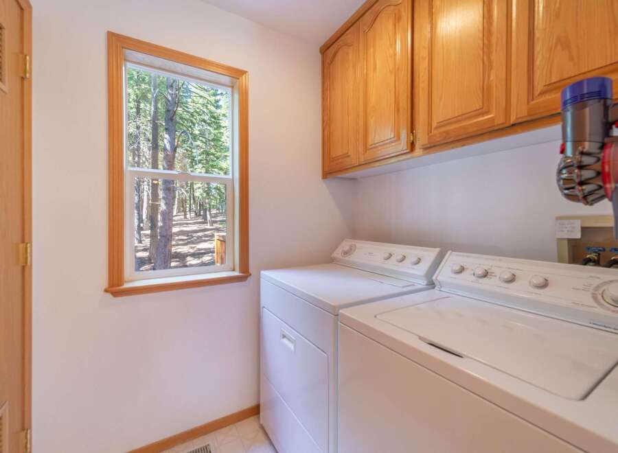 This laundry room offers a bright and functional space with a large window overlooking a serene forest.