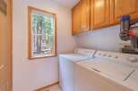 This laundry room offers a bright and functional space with a large window overlooking a serene forest.