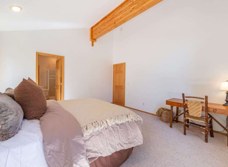 Experience rustic charm in this spacious bedroom featuring a vaulted ceiling with exposed wooden beams and a cozy sitting area.