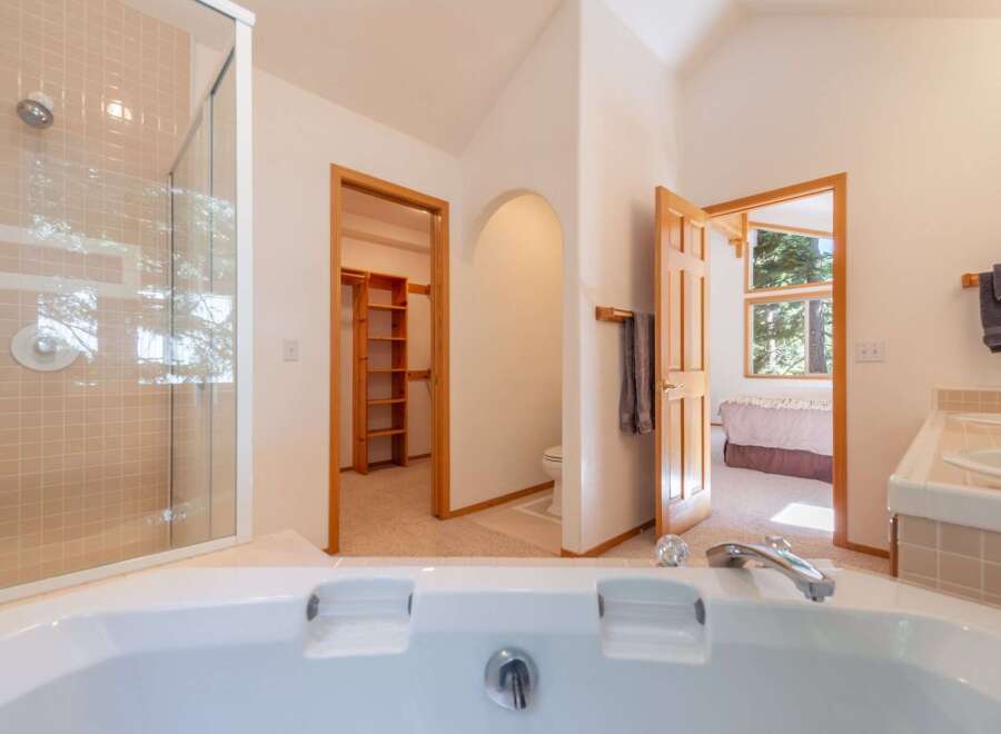 Experience luxury and convenience in this spacious bathroom featuring a large soaking tub and a separate glass-enclosed shower.