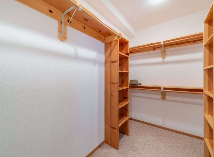 Discover ample storage in this spacious walk-in closet, featuring custom wooden shelving and hanging rods.