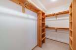 Discover ample storage in this spacious walk-in closet, featuring custom wooden shelving and hanging rods.