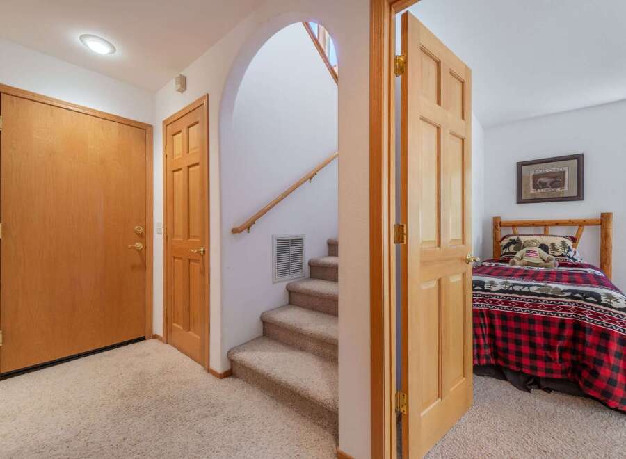 Step into this charming home featuring a cozy entryway with two wooden doors and a carpeted staircase leading to the upper level.