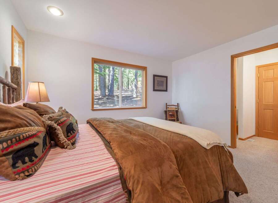 Experience rustic charm in this cozy bedroom, featuring a comfortable bed adorned with bear-themed pillows and a plush brown comforter.