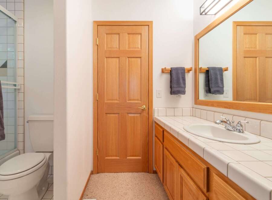 This bathroom features a wooden door, a white toilet, and a shower with tiled walls.