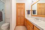 This bathroom features a wooden door, a white toilet, and a shower with tiled walls.